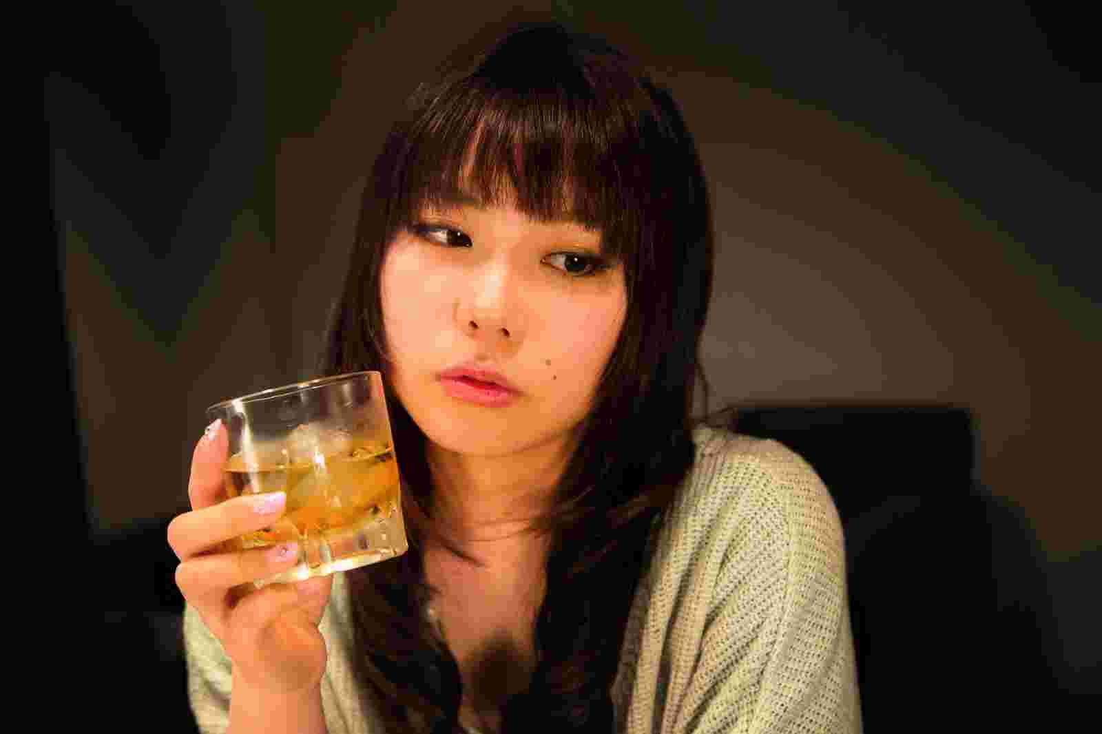 お酒を片手に物思いにふけっているような女性