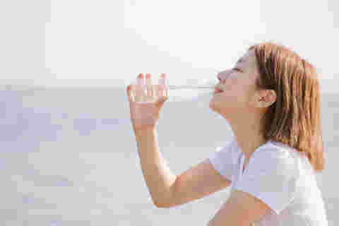 屋外でペットボトルの水を飲む女性