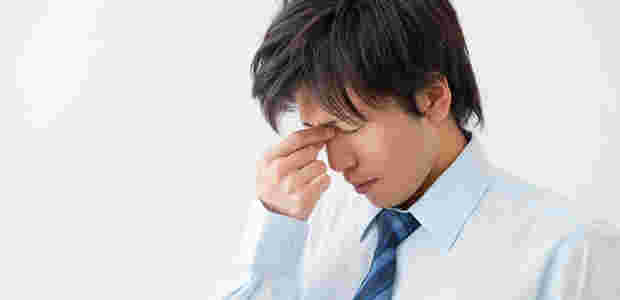 疲れ目で目頭を押さえる男性