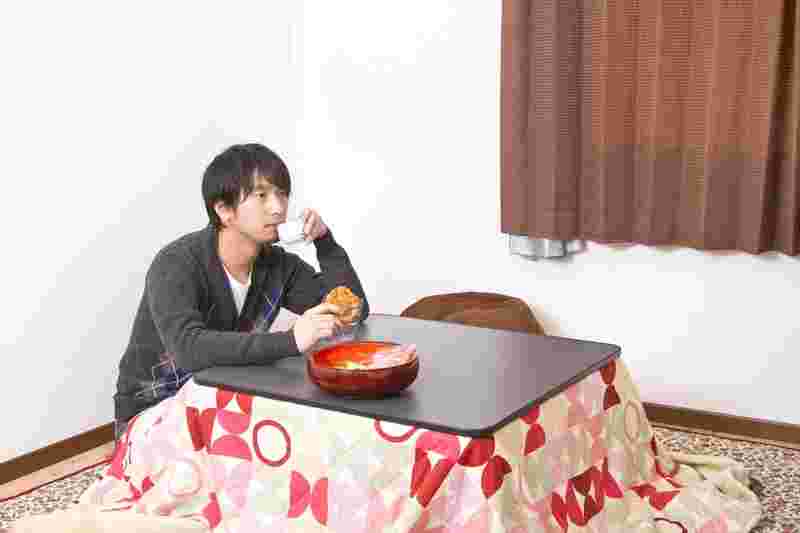 こたつでお茶を飲んでいる男性