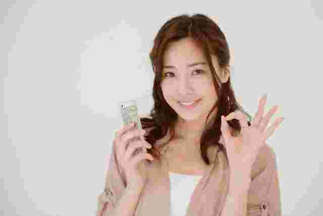 スマホを片手にオッケーサインをする女性