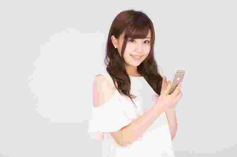 スマートフォンを手に持って笑顔の女性
