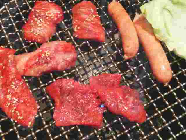 網の上に置かれたウインナーと肉と野菜