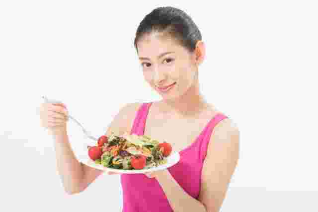 お皿いっぱいに入ったサラダを持つ女性
