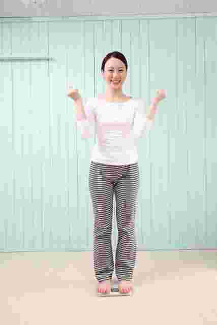笑顔で体重計に乗る女性