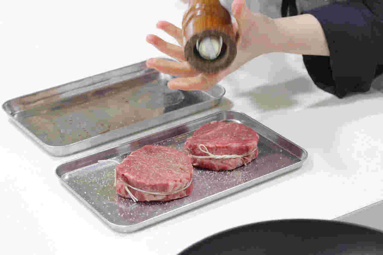 ステーキに塩コショウを振っている様子