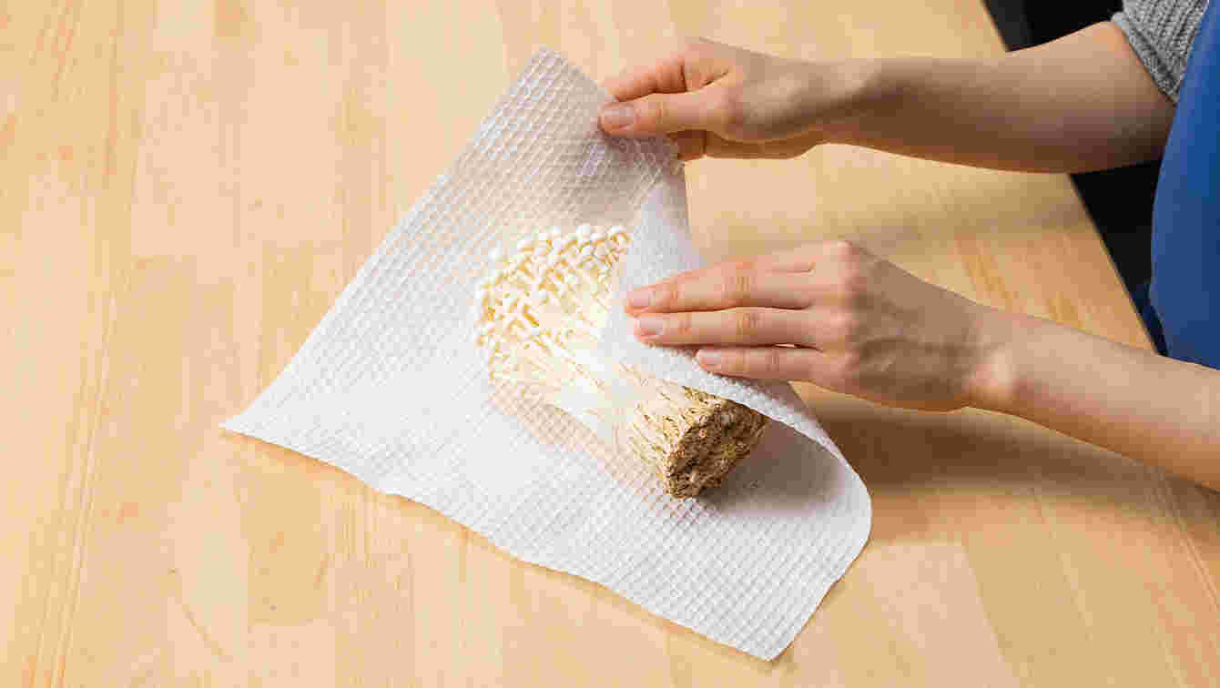 木製の台の上でえのきをキッチンペーパーで包む