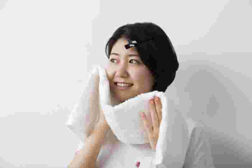 タオルで顔を触る女性画像