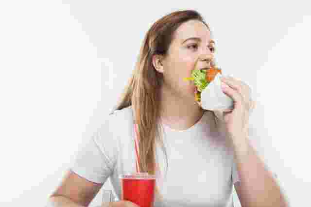 大きな口を開けてハンバーガーを食べている女性