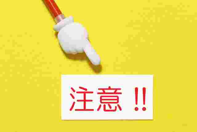 人差し指を伸ばしたおもちゃのステックが白色の紙に赤文字で注意と書かれた紙をさしている
