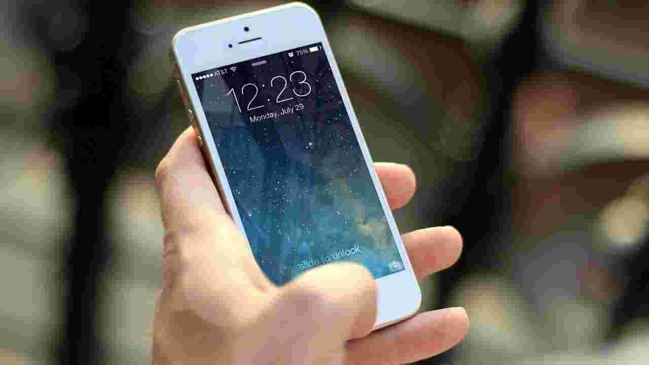 左手でスマホを持ち親指でボタンを押そうとしている