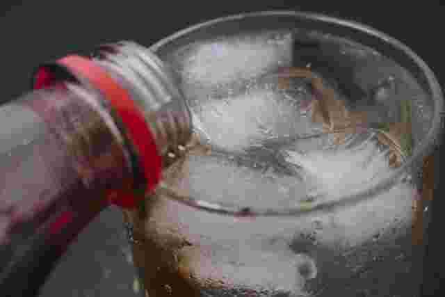 グラスにコーラを注いでいるアップ