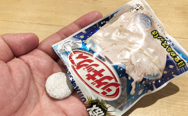 左手を裏にして丸い白い塊を乗せて、封が開いている四角いパッケージも一緒に乗せている