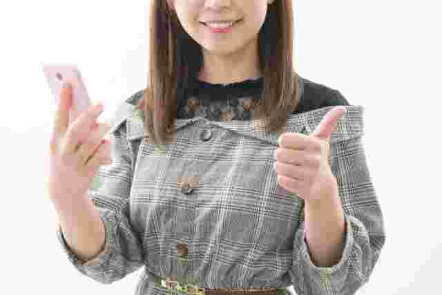携帯持ってgoodサインする女性