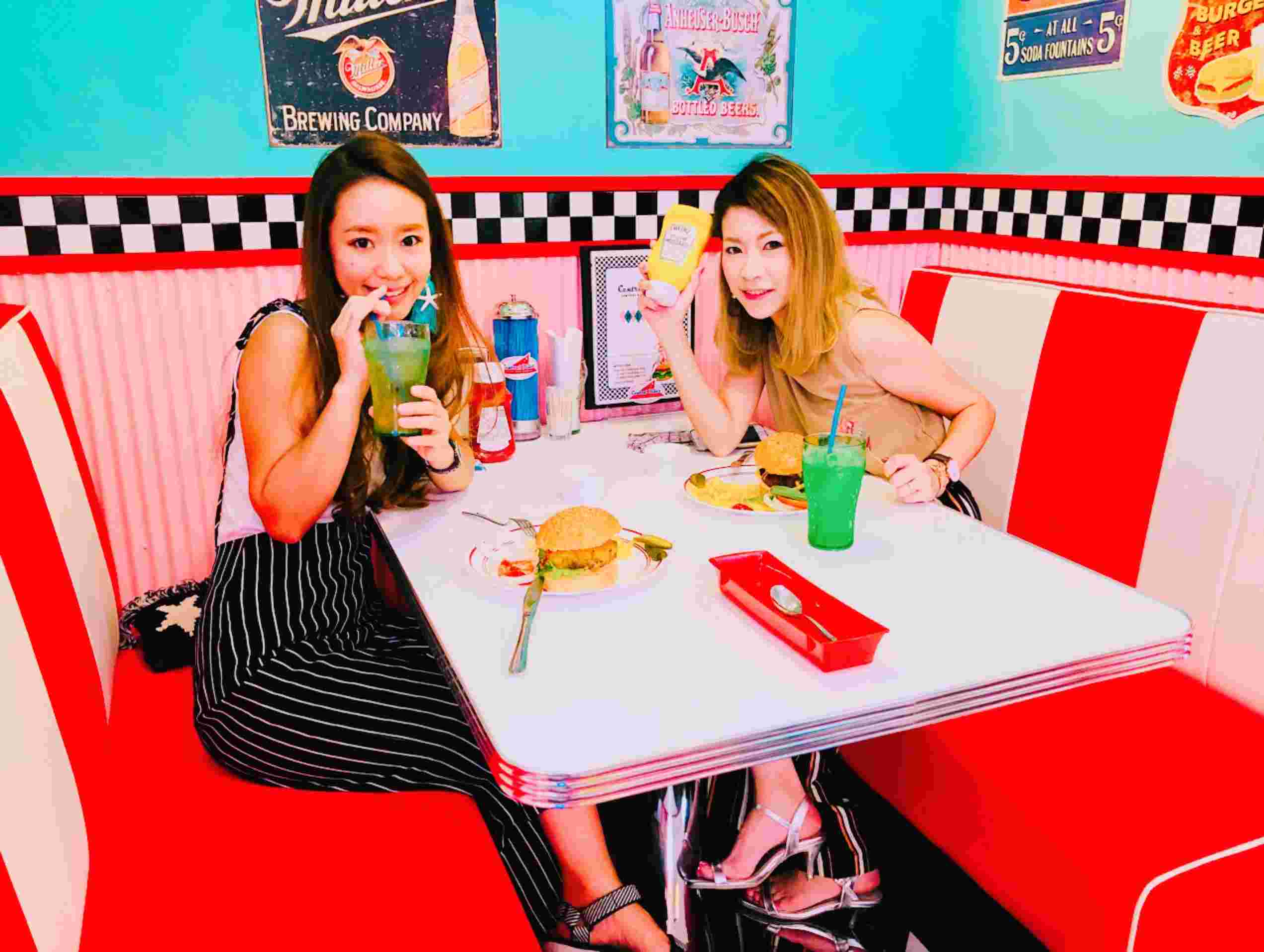 愛知県常滑市にあるセントラルダイナーの店内でハンバーガーを食べながらポーズをとる女性