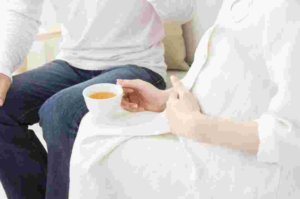 飲み物を飲んでいる妊婦の女性と夫