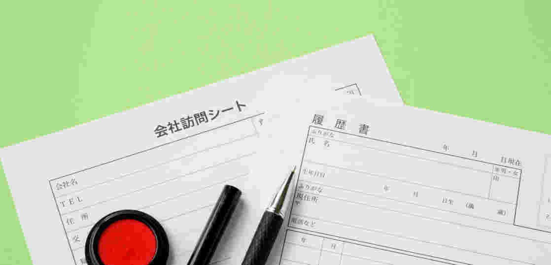会社訪問シートと履歴書が重ねられ、朱肉とペンが並んでいる様子