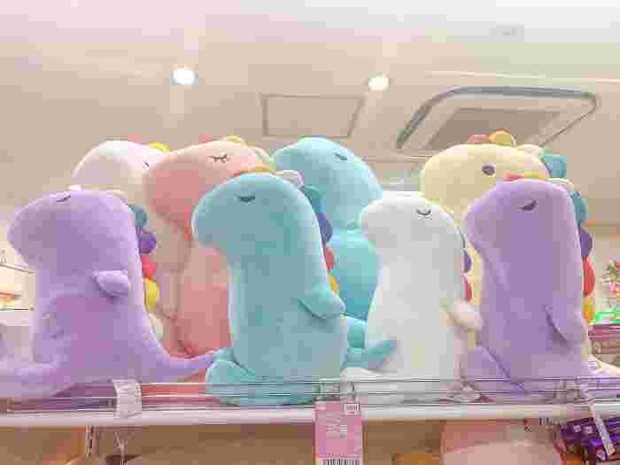 棚の上にコンパクトサイズの恐竜のぬいぐるみが多数置かれている