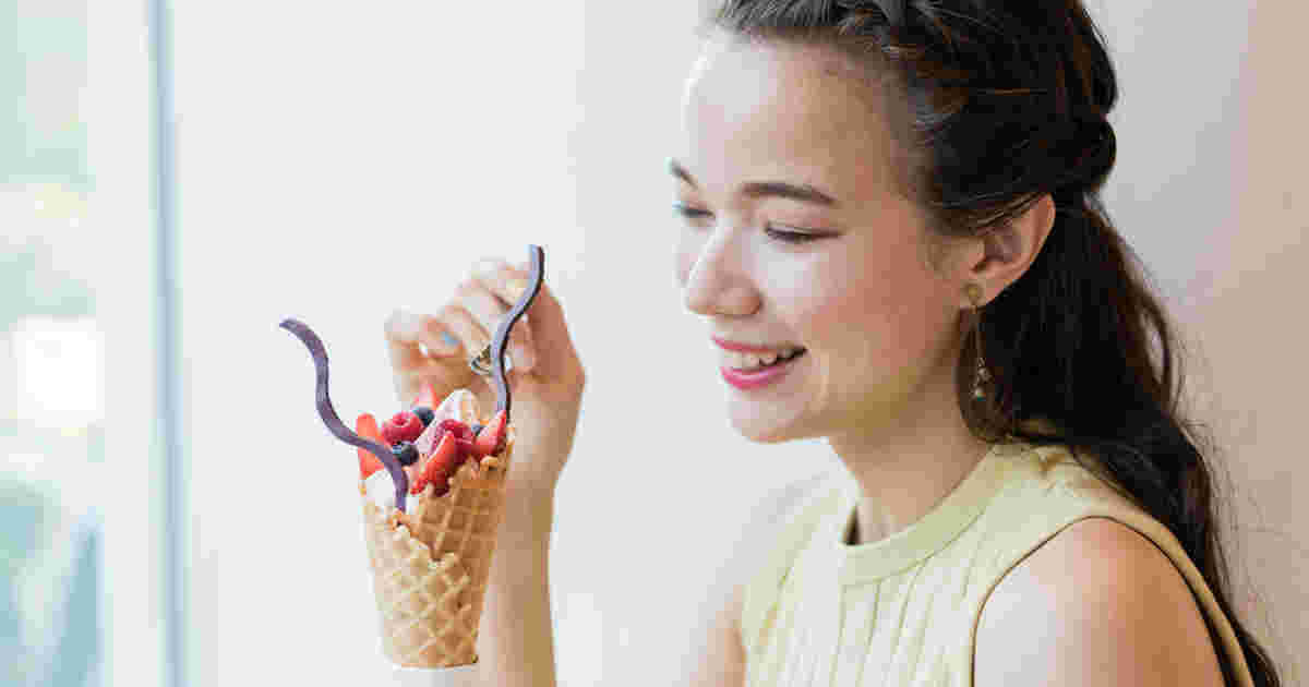 フルーツたっぷりのジェラートを手に、スプーンですくおうとしている女性