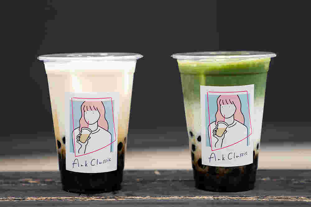 女性のイラストが描かれたタピオカドリンクのコップ