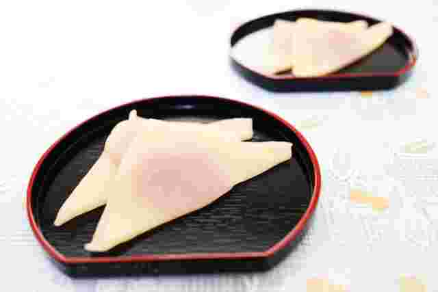 手前に漆の皿にピンクの餡が包まれた生八ツ橋が２つ載っている。同じものが奥にもある。