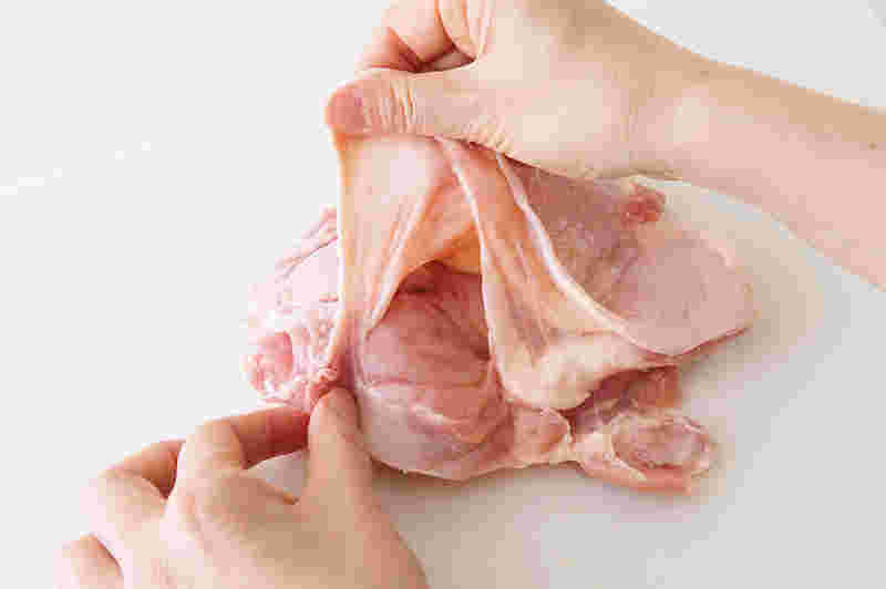 鶏肉の皮を手で剥がしている様子