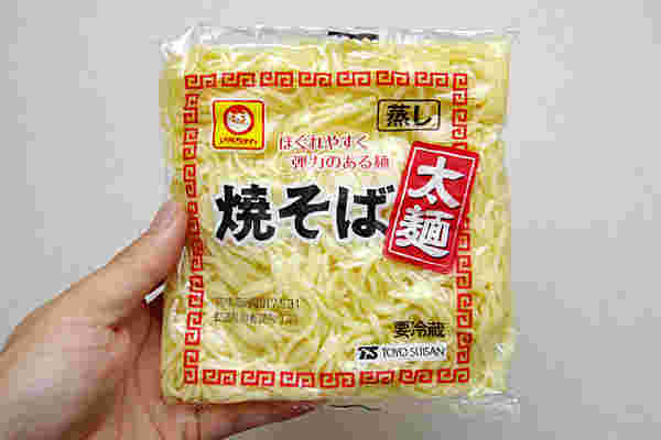 焼きそば用の蒸し麺を手に持っている