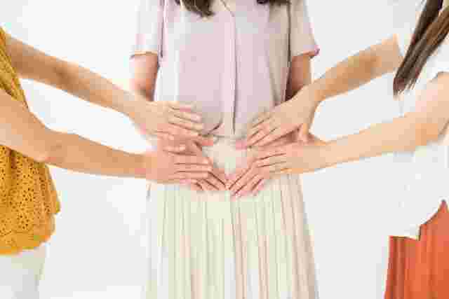 一人の女性に両端から女性がお腹を支えている様子