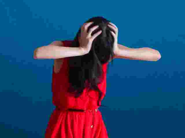 頭を抱える赤いワンピースの女性