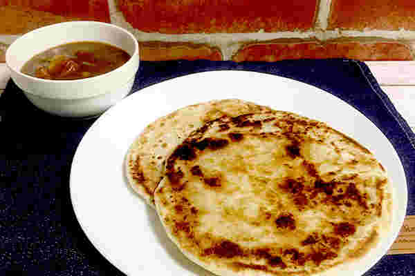 お皿に盛りつけられたパラタと小鉢に入ったカレーがテーブルに並べられている