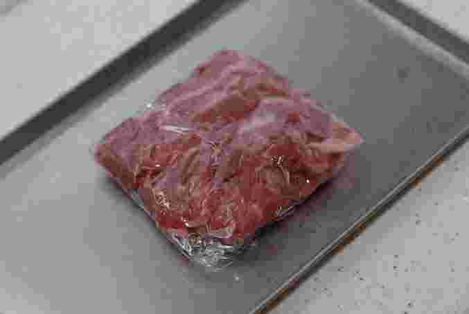 ラップで包んでいる牛肉を金属トレーに乗せている様子