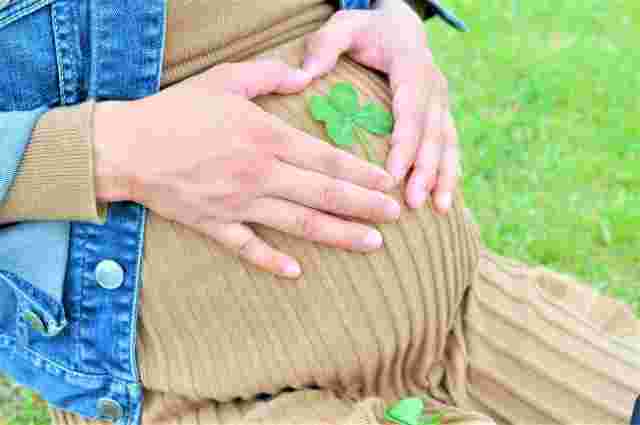 お腹に四葉のクローバーをのせている妊婦さん