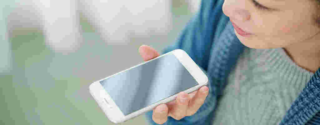 スマホのイヤホンジャックに息を吹きかける女性