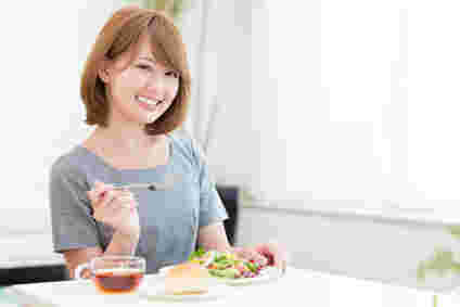 ダイエットを意識してサラダとパンを食べている女性
