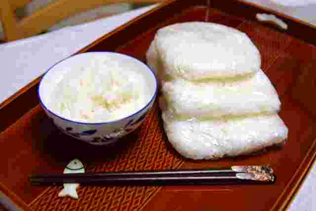 お盆にのせた茶碗に入ったご飯とラップに包んだ冷凍ご飯