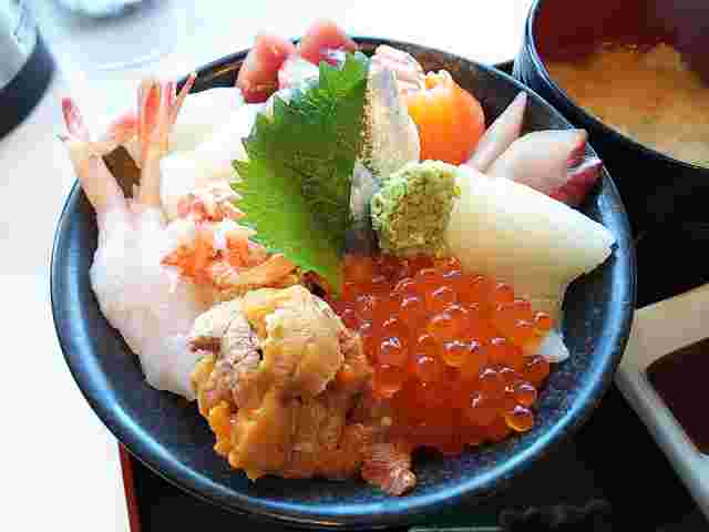 黒いどんぶりに入った様々な魚介が乗った福井の海鮮丼