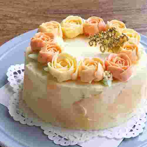 華やかな花の飾りが美しいバタークリームケーキがお皿に乗っている様子