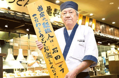 看板を持っている丸亀製麺の麺職人