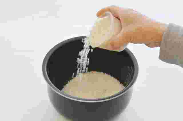 炊飯釜に米を入れる手