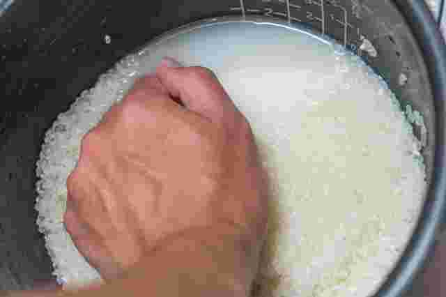 炊飯釜で米を研いでいる手