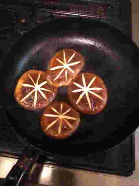 フライパンで焼かれている4つのしいたけ