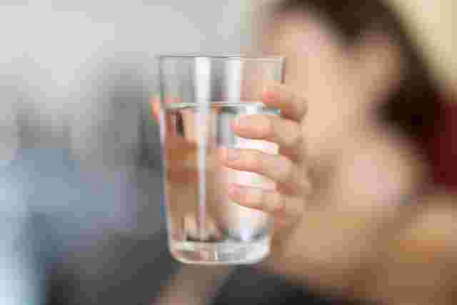 コップに入った水を飲む女性