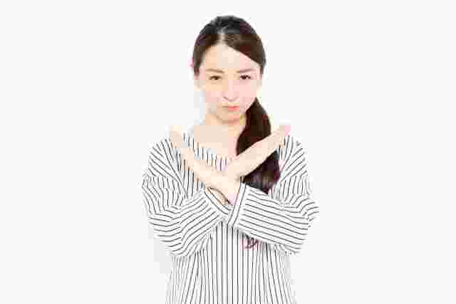 胸の前で腕をバツにする女性