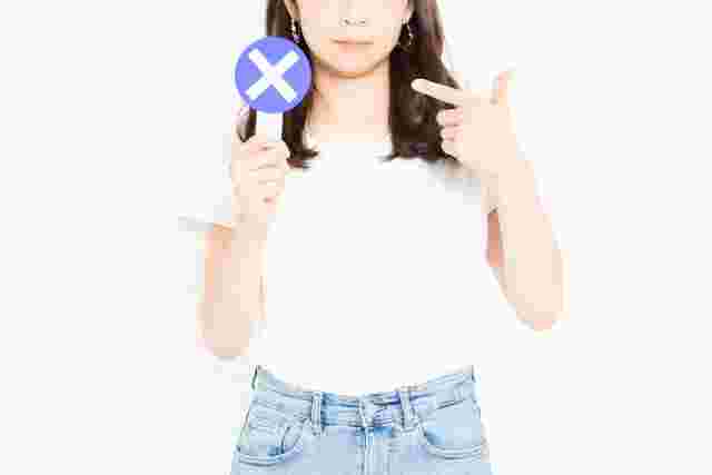 持っているバツマークを指差す女性