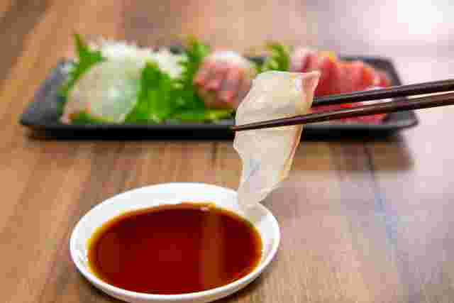 箸で持ち上げて醤油につけている鯛の刺身