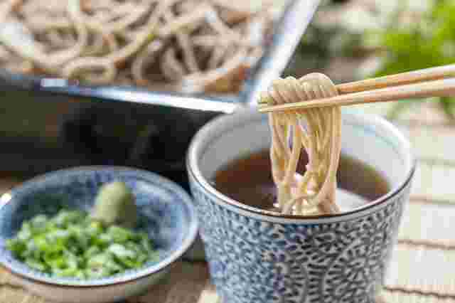 蕎麦を箸でつまんでめんつゆにつけている様子