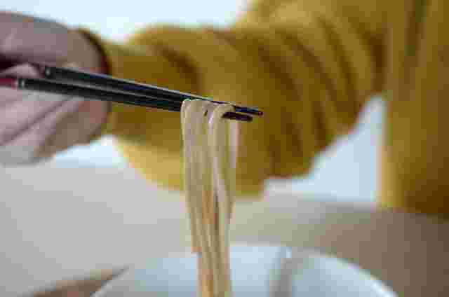 蕎麦を箸でつまんでいる女性