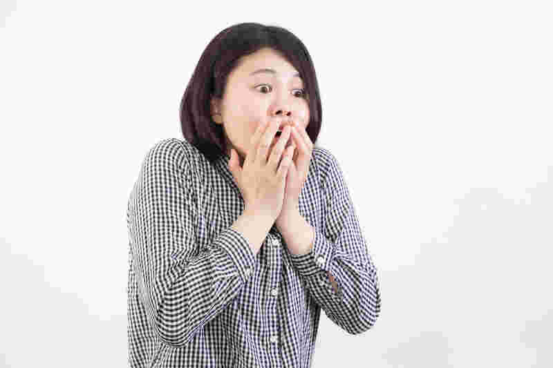 口に手を当てて驚く女性
