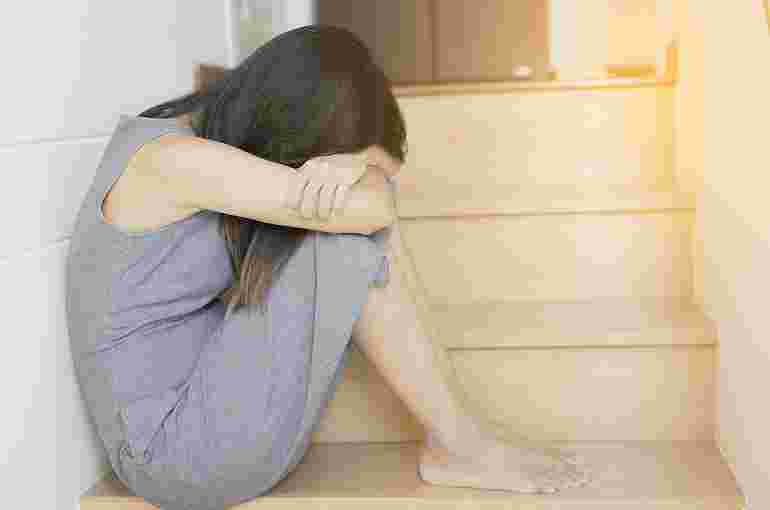 膝を抱えて具合が悪そうな女性