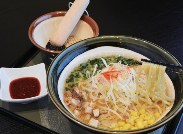 様々なトッピングをされたラーメンとごまの入った小さなすり鉢